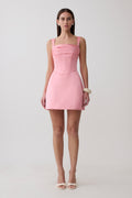 Woman wearing a pink satin corset mini dress.