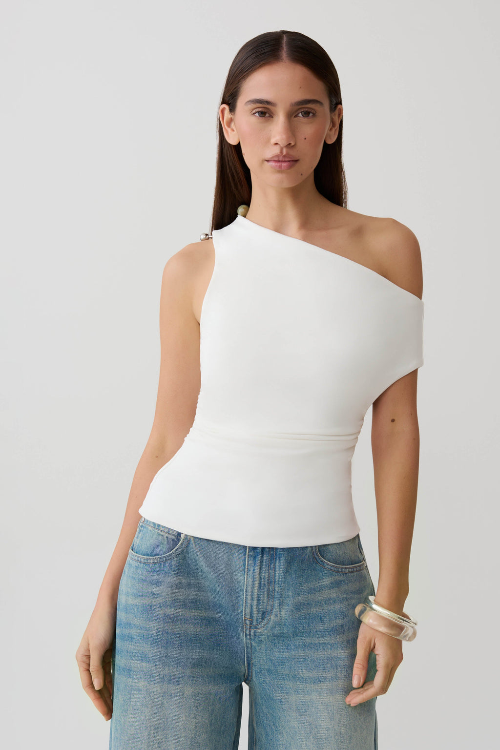 Woman wearing a white short sleeve draped hardware top.