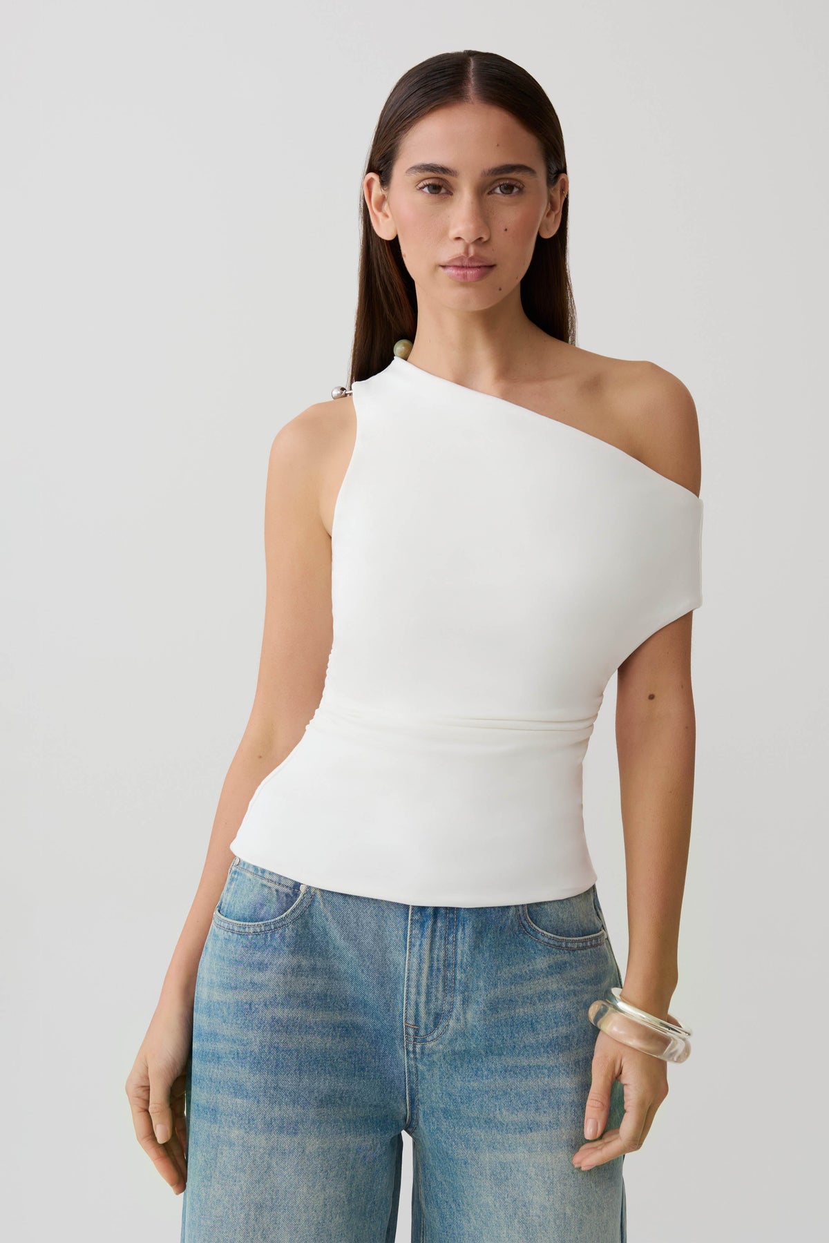 Woman wearing a white short sleeve draped hardware top.