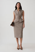 A woman models a sleeveless taupe houndstooth vest and matching pencil skirt set, holding a brown clutch against a light gray studio background.