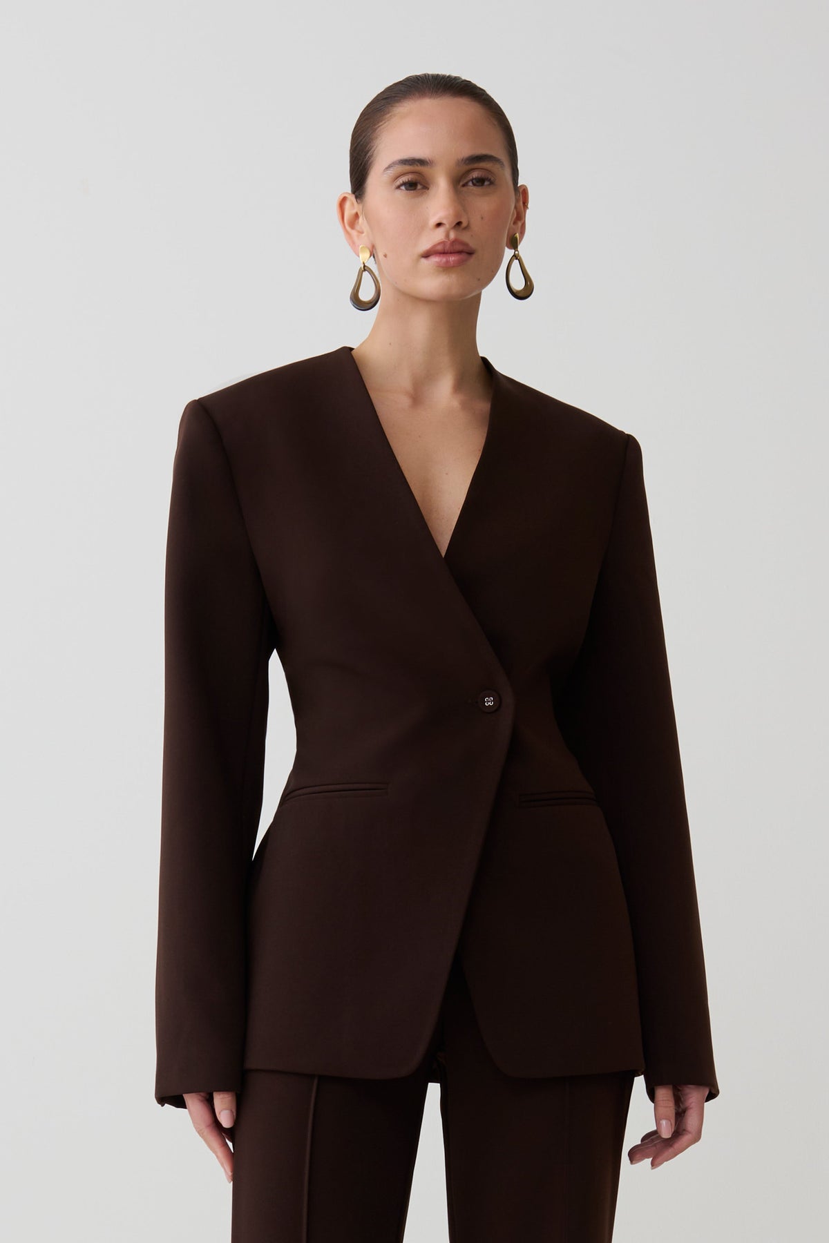Woman wearing dark brown drop shoulder suiting blazer.