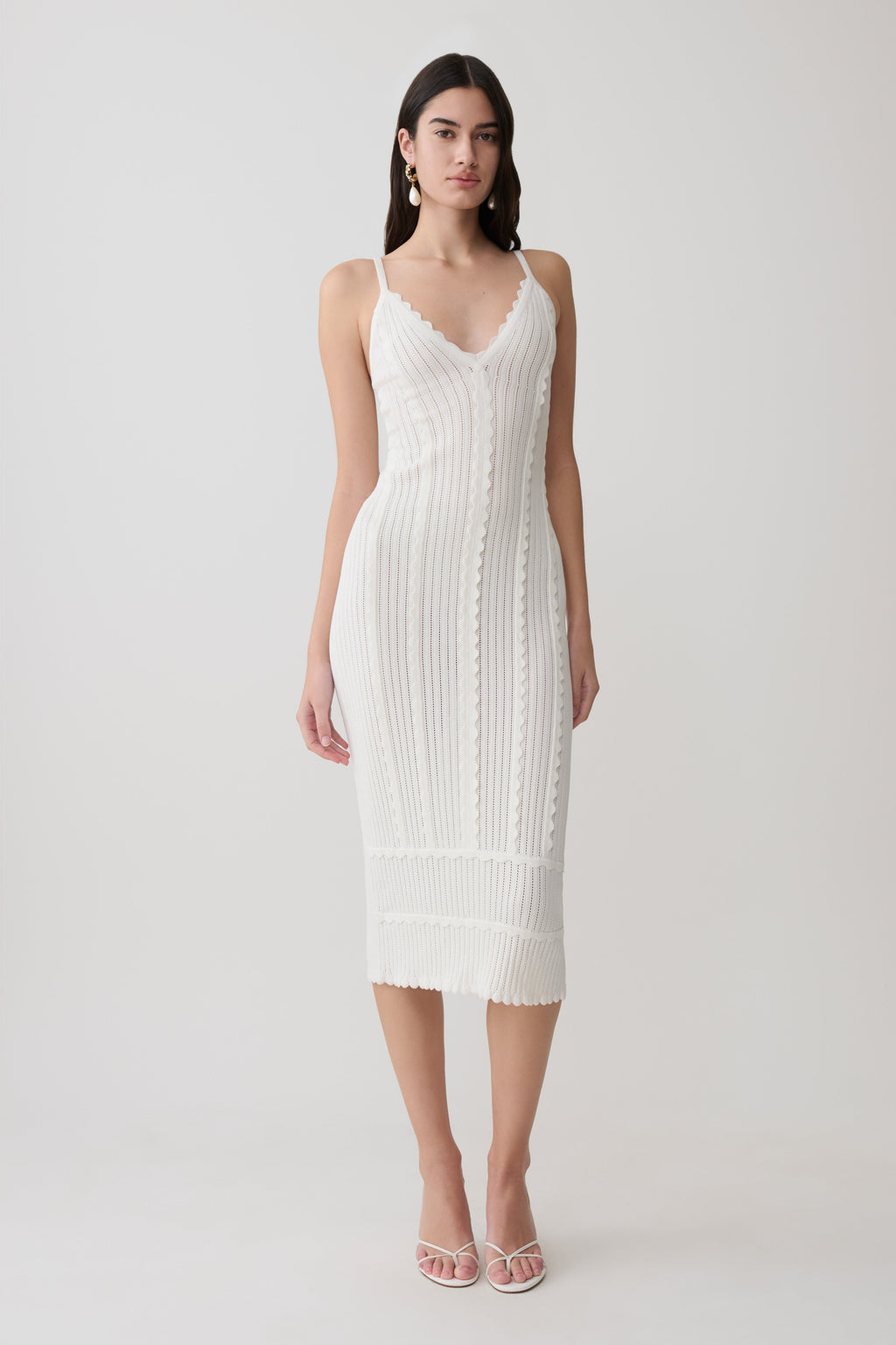 Woman wearing a white scalloped neckline pointelle midi dress.