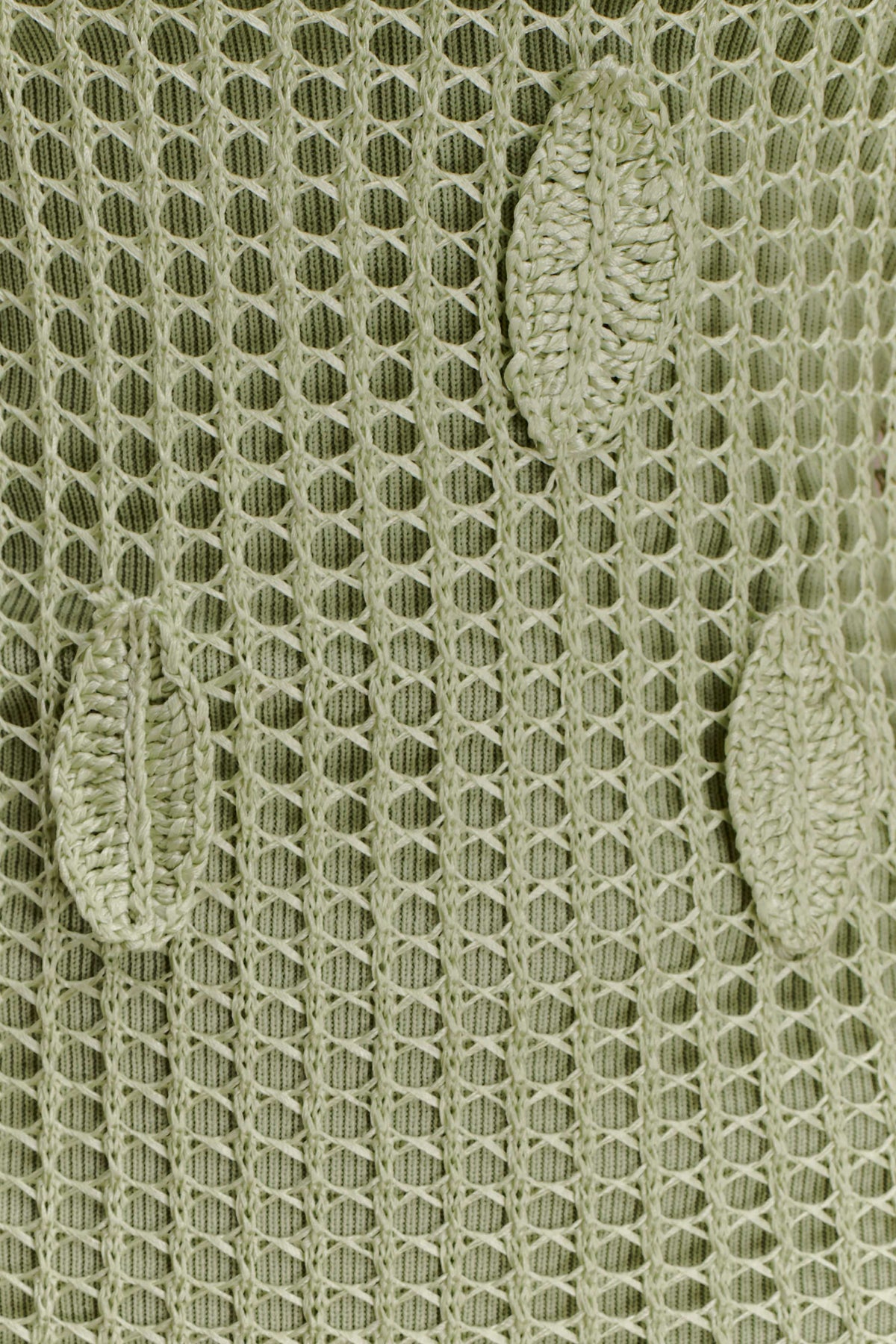 Close-up of a textured green crochet fabric with leaf detailing.