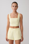 Woman wearing a light yellow sleeveless top and matching shorts.