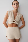 Woman wearing a beige tie front short sleeve top with matching shorts.