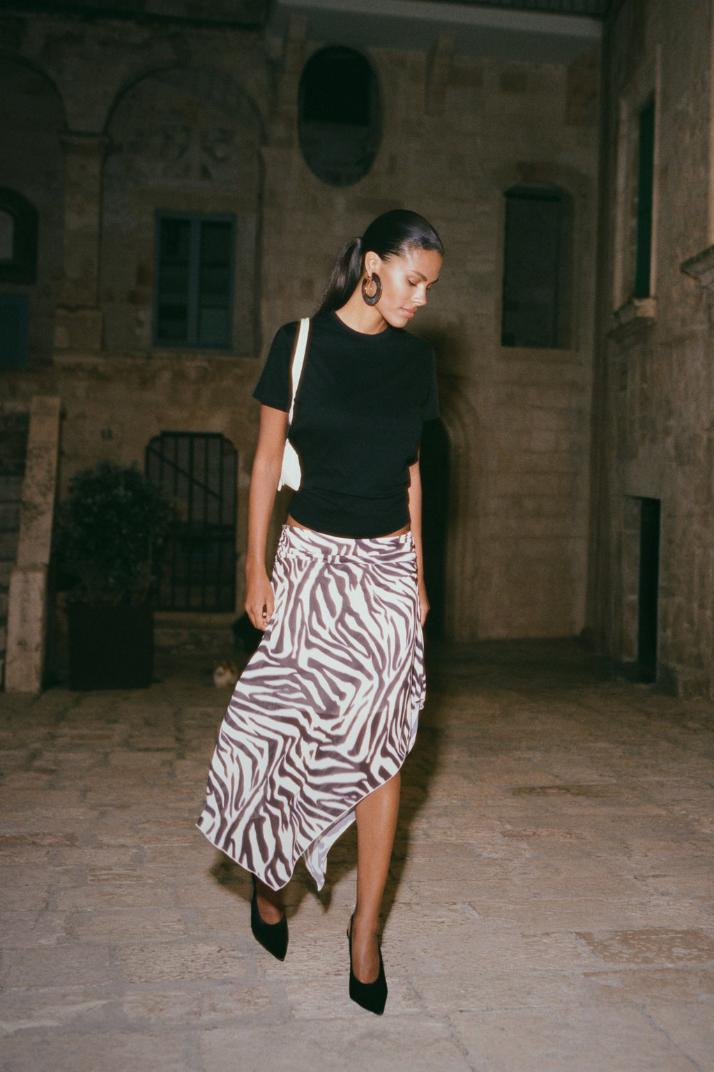 Woman in black top and zebra print chiffon midi skirt.
