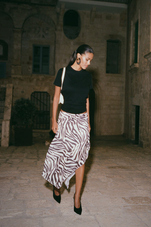 Woman in black top and zebra print chiffon midi skirt.